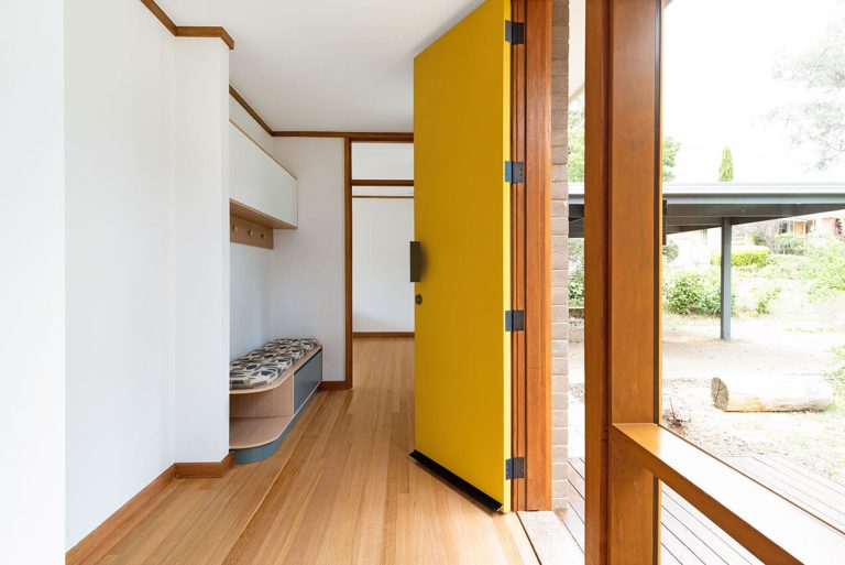 Image shows a yellow front door and modern house entryway.