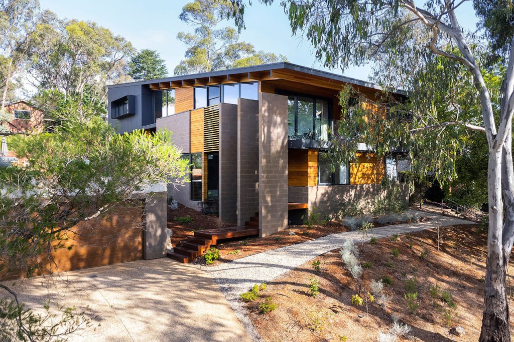 Image shows an image of a modern energy efficient house set among trees.