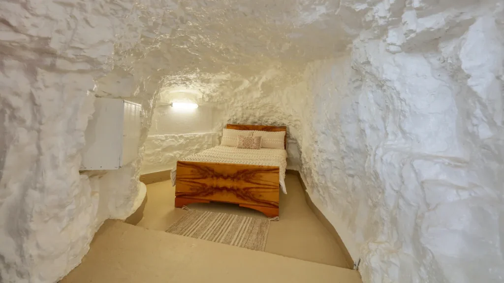 Image of a bedroom in an underground house of white cliffs, nsw. The house has no underslab insulation, just the rock surface.
