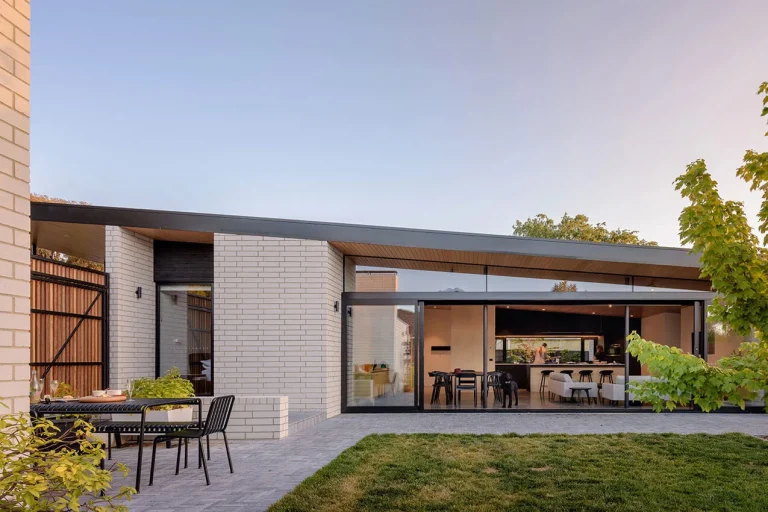 Image of exterior of house looking through large open glass doors into open plan living, 7.4 star house designed by Ben Walker Architects and energy rating by Powerhaus Engineering.