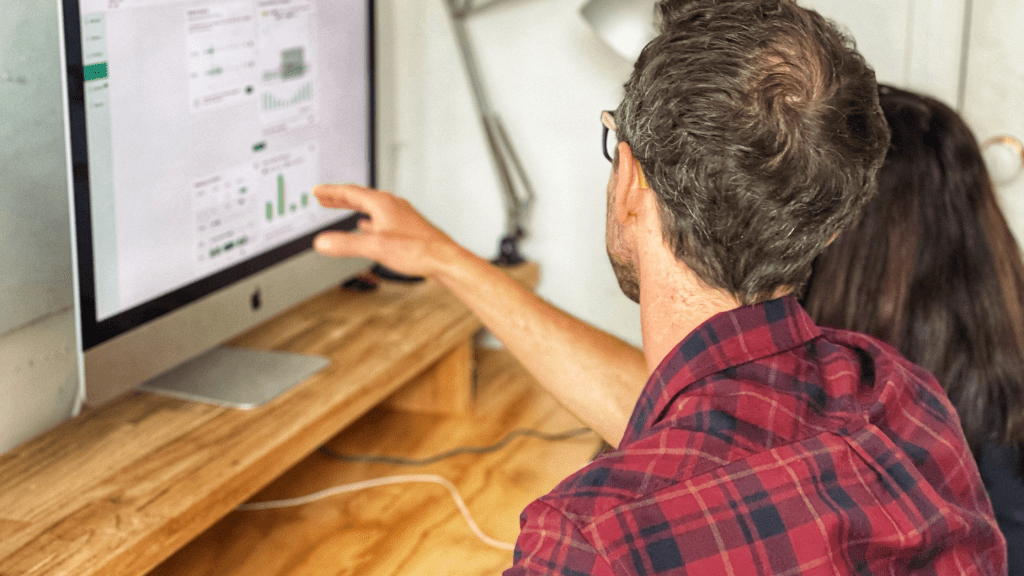 Image of a Powerhaus team member pointing at a Performance Solution report on a computer screen.