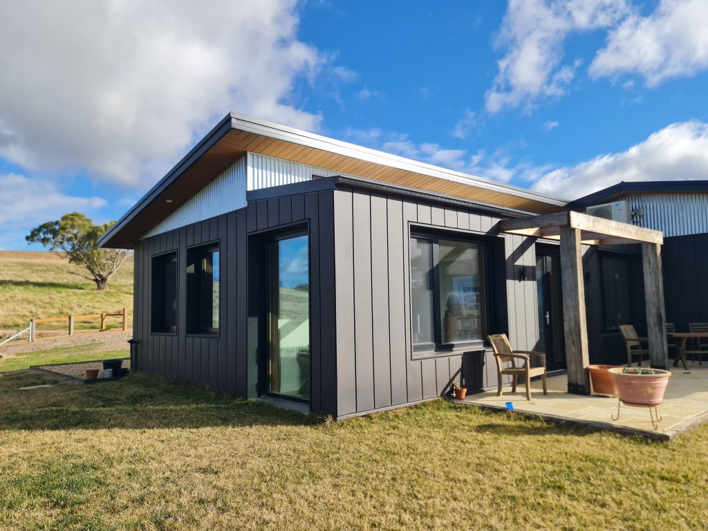 Exterior shot of the sustainable house showcasing skillion roof and north-facing glazing, with open pergola.