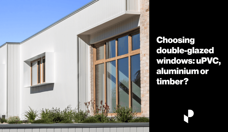 Image of a modern house exterior with large double glazed timber windows allowing sun through.